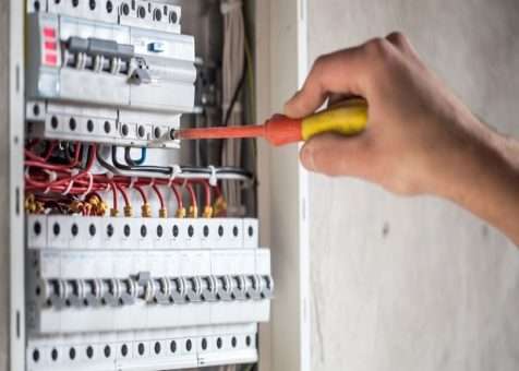 An-Mackay-electrician-upgrading-a-switchboard-in-Richmond-Image-shows-a-man-with-a-screwdriver-on-a-circuit-breaker